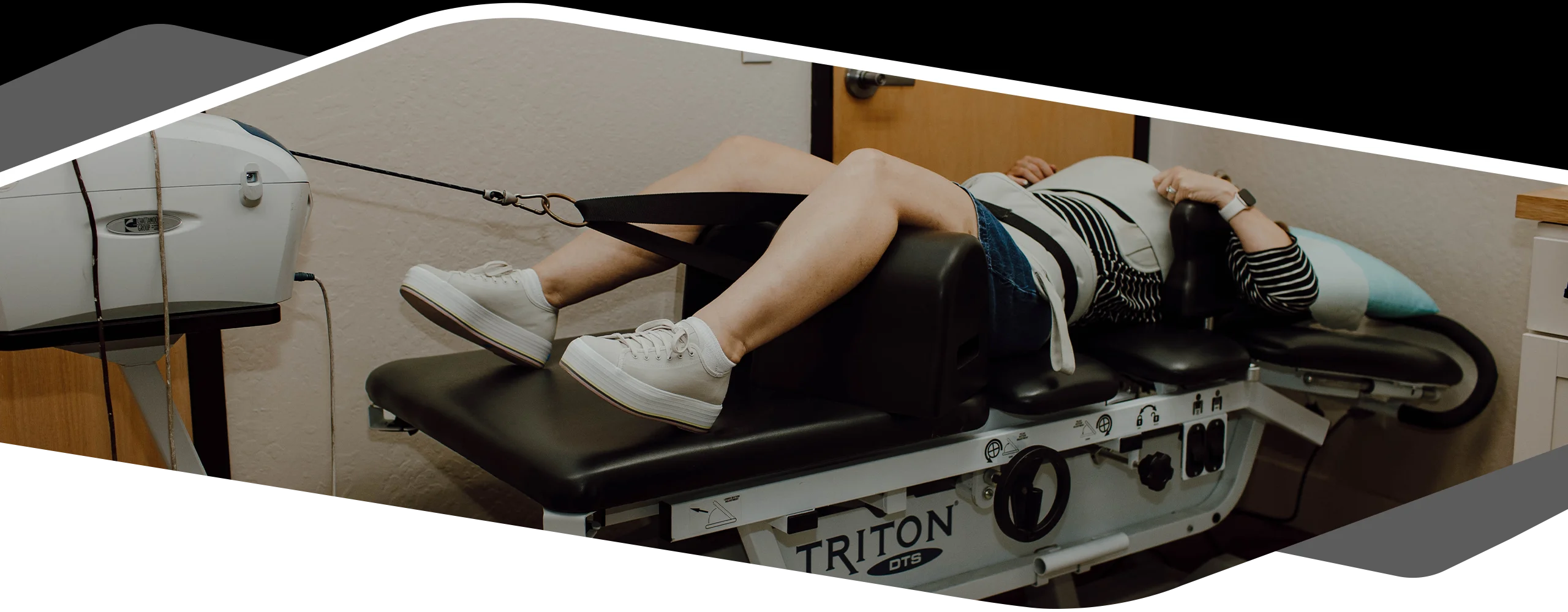 Person lying on a traction therapy table with straps attached to the lower body, undergoing spinal decompression treatment in a clinical setting